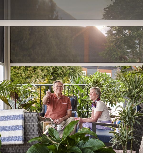 Elderly couple sitting on patio with motorized retractable screens