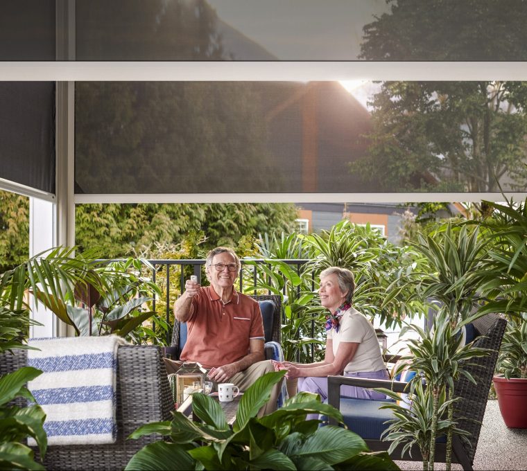 Elderly couple sitting on patio with motorized retractable screens